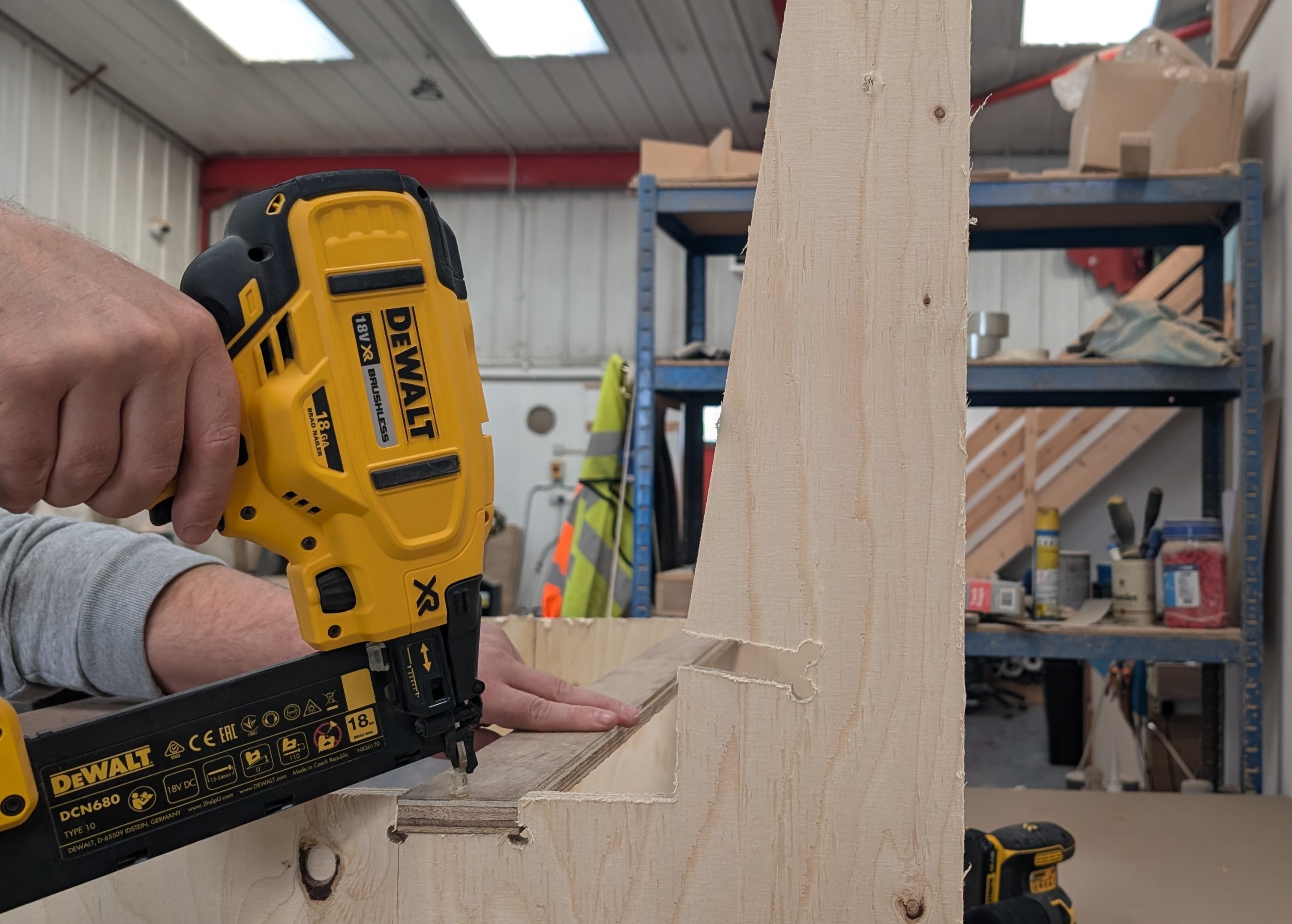 Carpenter nailing a plywood seating frame in the workshop