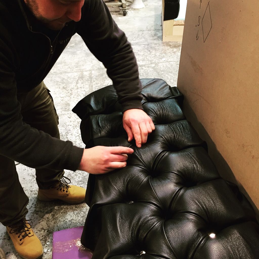 Upholsterer deep buttoning a leather bench