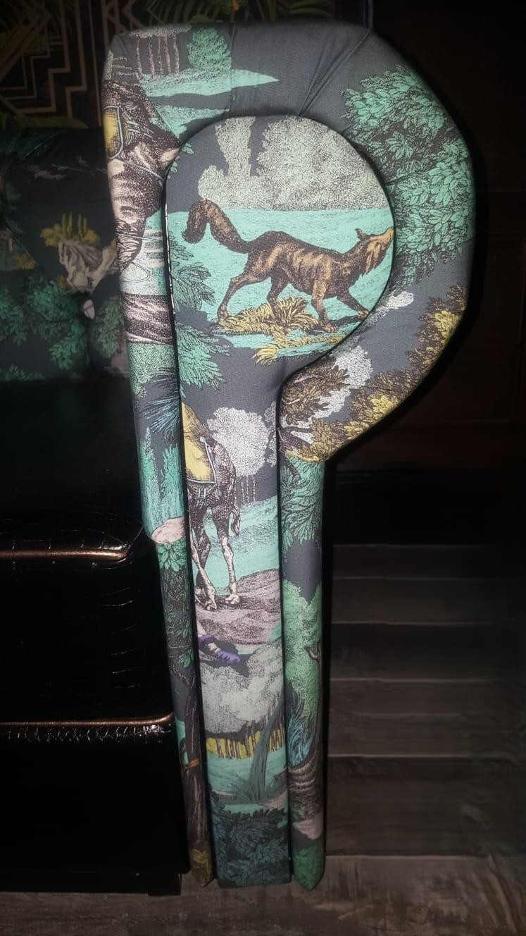 Scroll-shaped armrest upholstered in a green toile safari print, made to match a printed banquette.