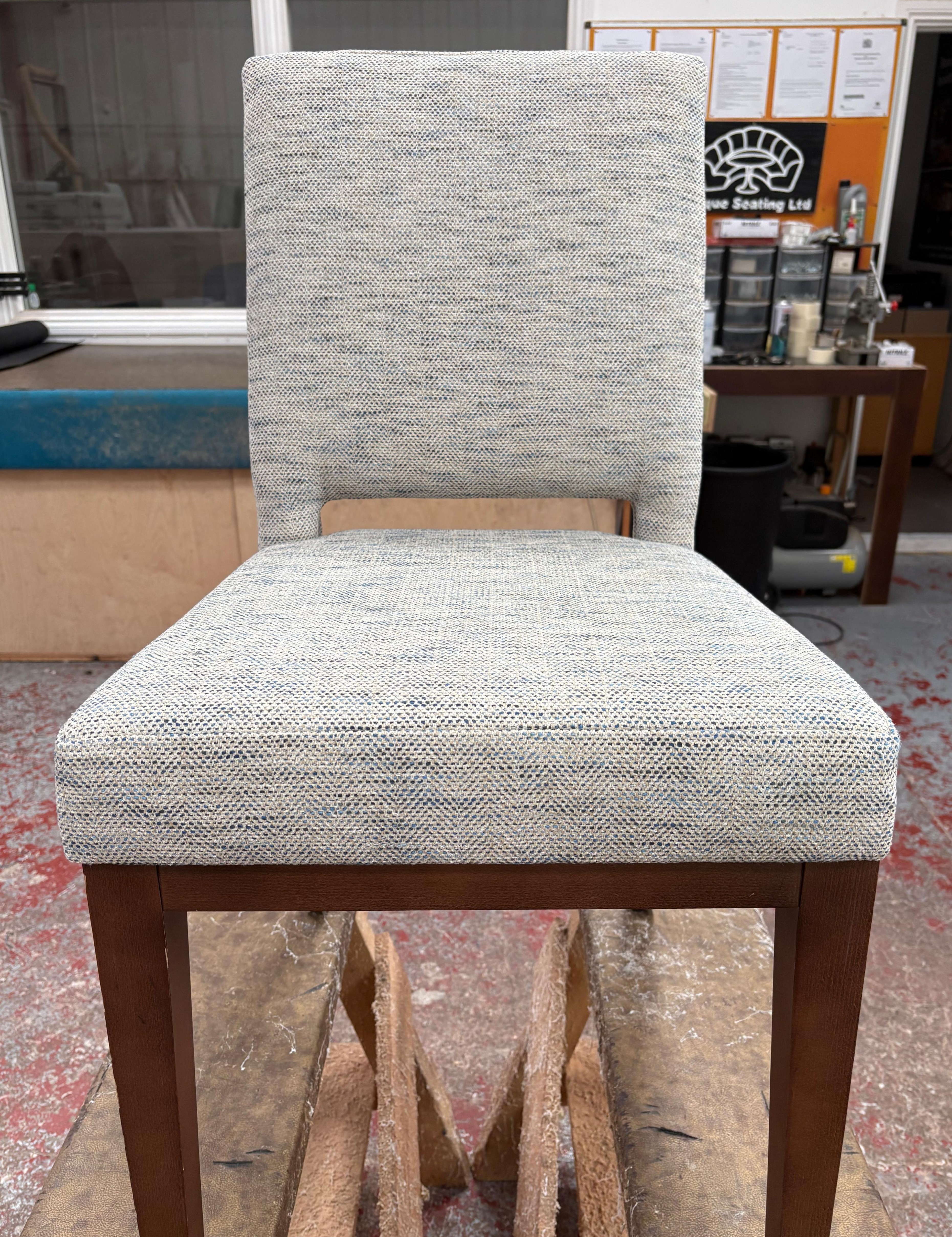 Dining chairs reupholstered in a blue-grey tweed with dark stained frames, photographed in the workshop.