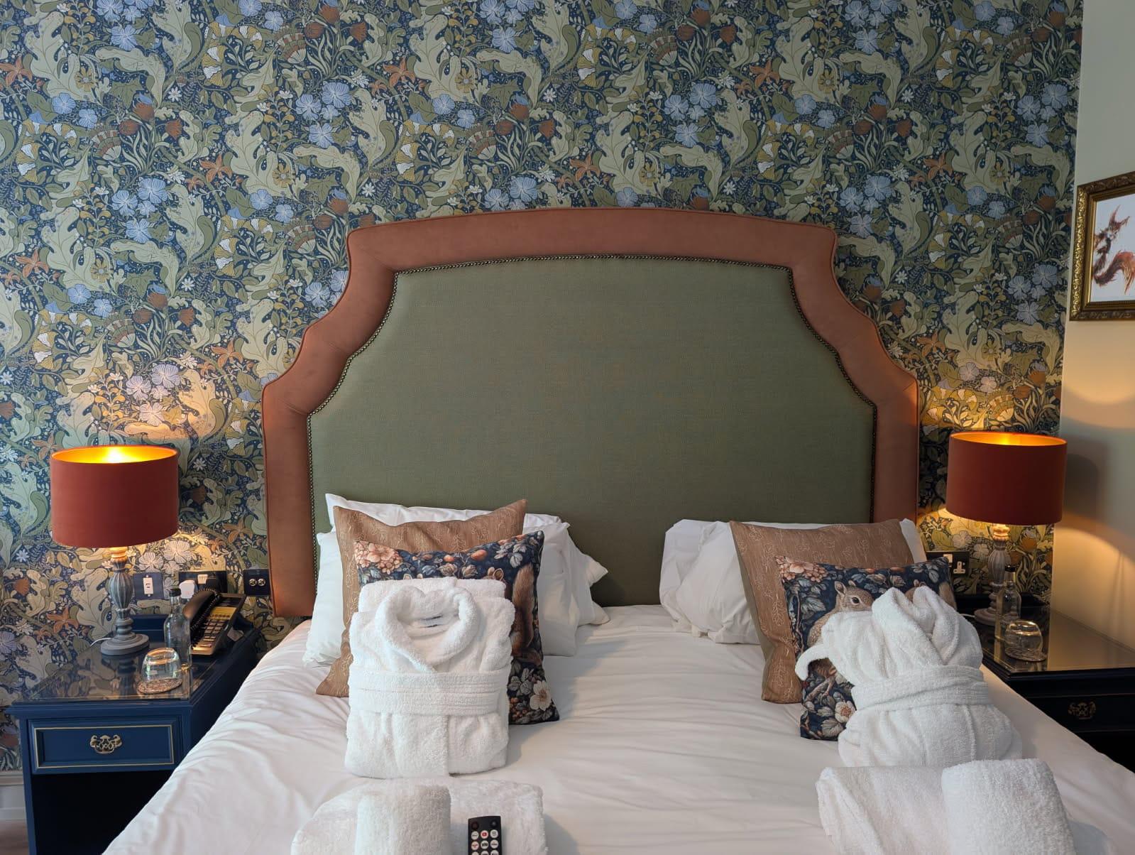 Shaped hotel headboard with a sage linen centre panel framed in rust velvet and finished with a stud border.