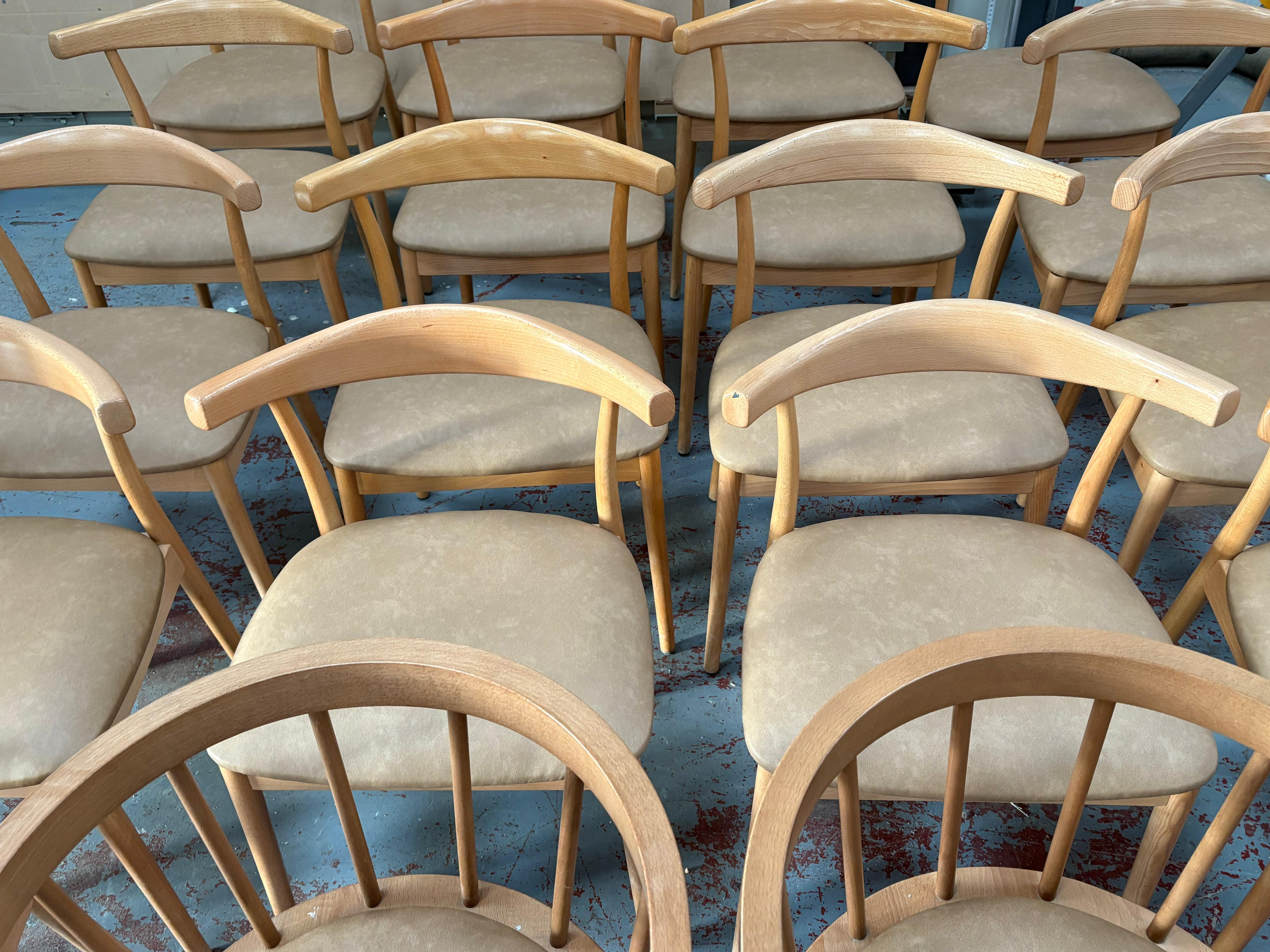 Batch of beech carver chairs with new taupe faux leather seats, lined up in the workshop before delivery.