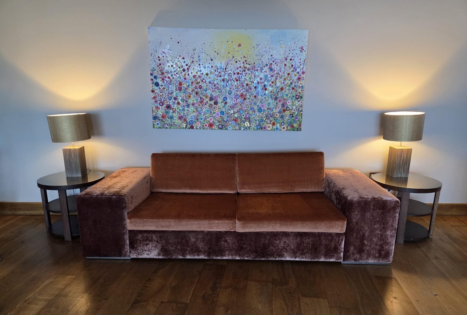 Wide three-seater sofa in crushed copper velvet with deep square arms, set between lamp tables in a hotel lounge.