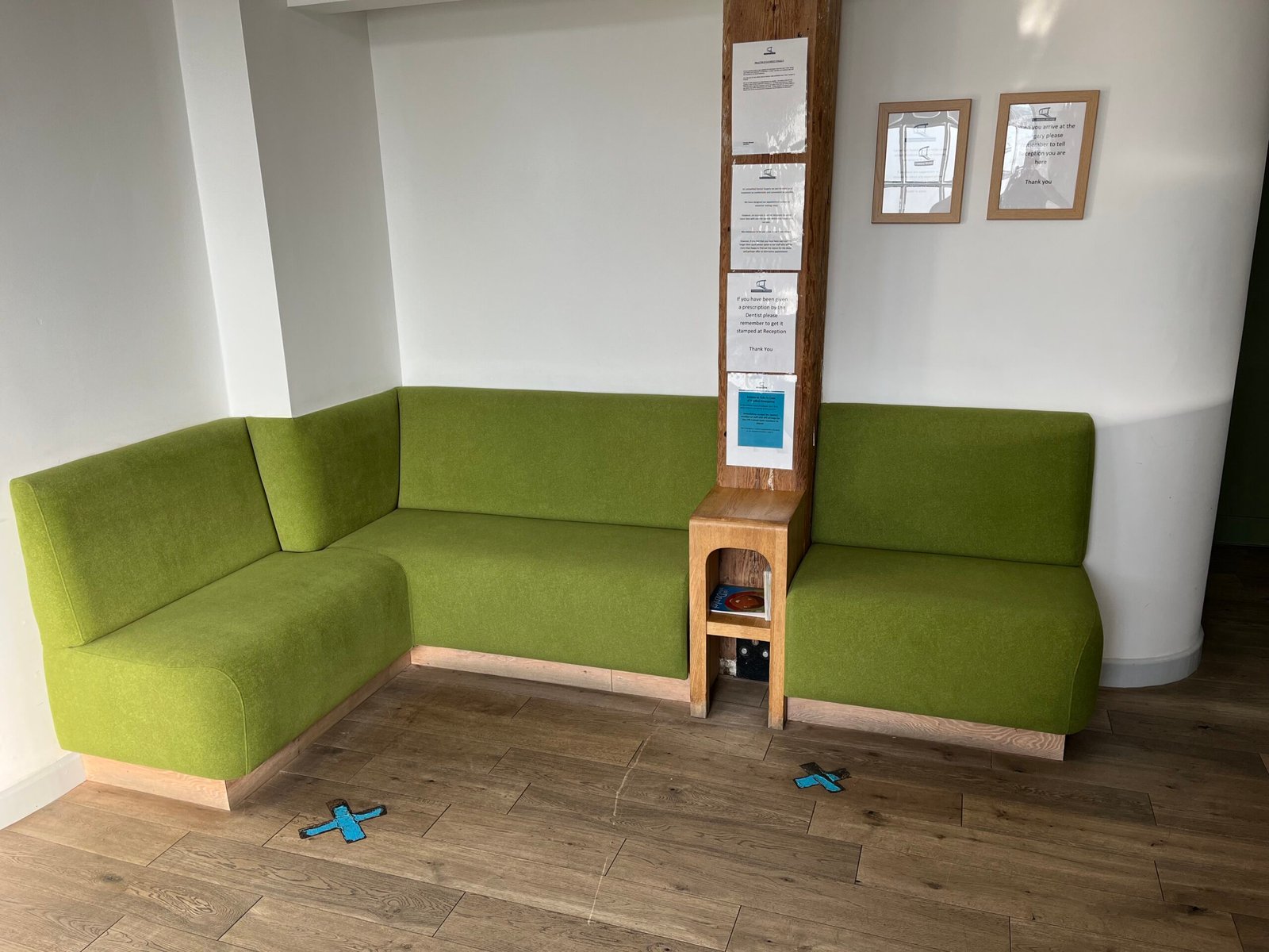 L-shaped waiting room bench in lime green wool with a light oak plinth, built around a structural post.