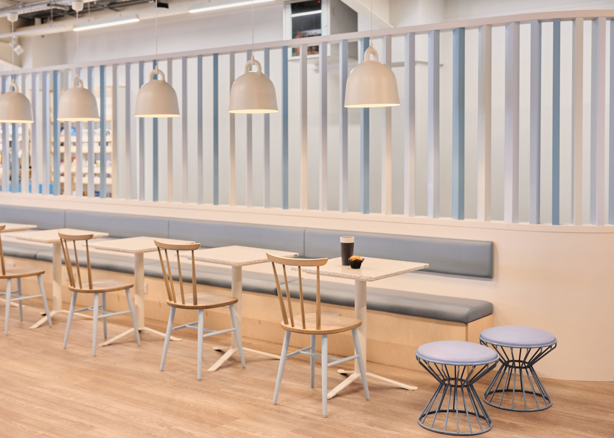 Long low-back bench in pale blue leather built into birch joinery, running the length of an airport cafe.