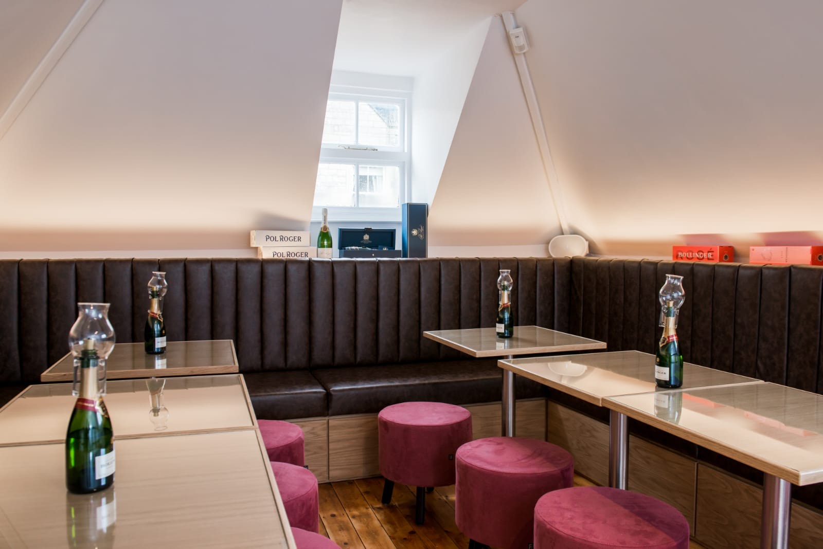 Full-length fluted banquette in dark brown leatherette with a display shelf above and pink velvet stools below.