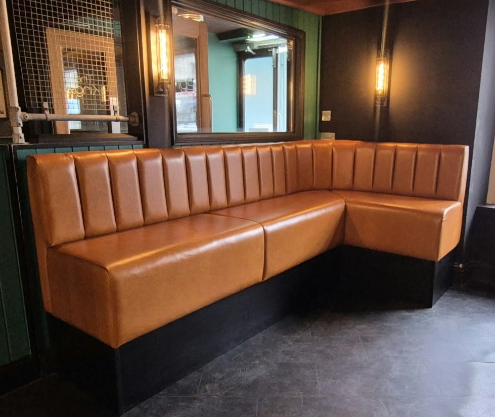 Tan fluted L shape banquette seating in a nightclub