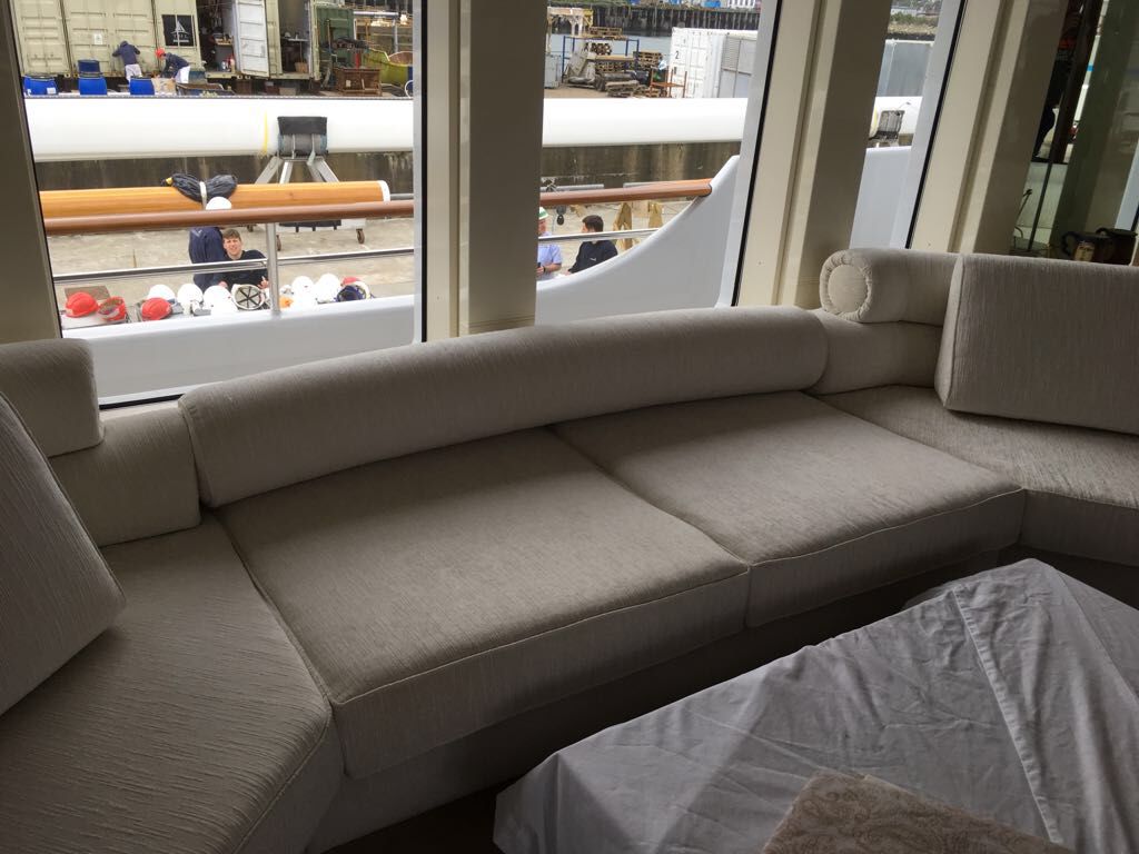 Modular cream corner seating with bolster cushions, fitted to the curve of a yacht saloon during build.