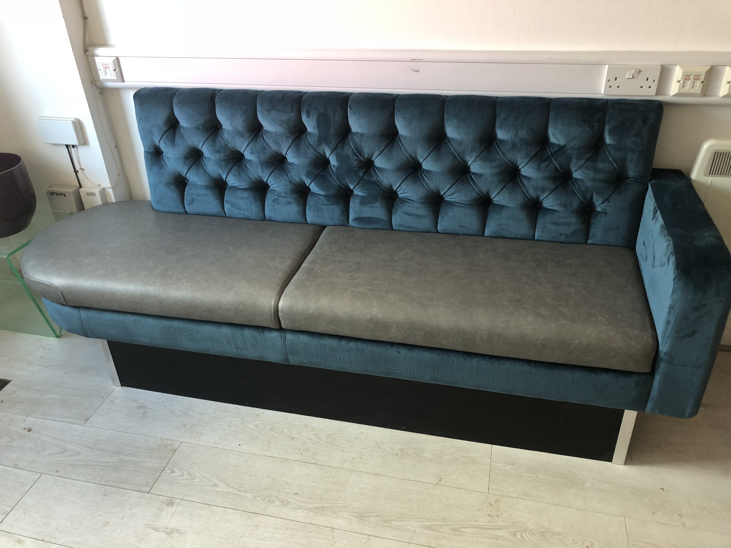 Compact bench with a deep-buttoned teal velvet back and grey faux leather seat, sized for reception and waiting areas.