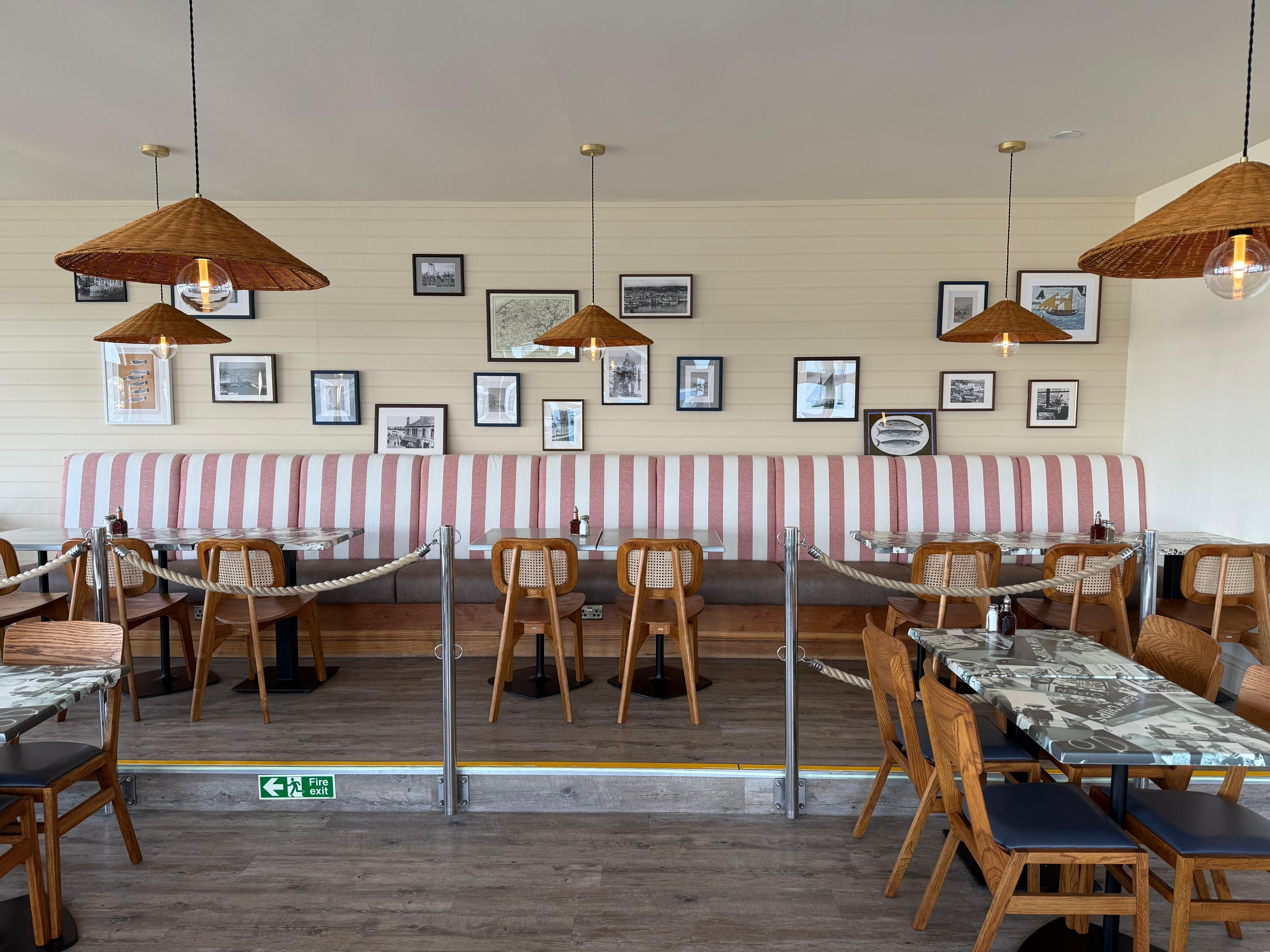 Long banquette with a bold pink and white striped back and brown leather seat, in a seaside restaurant